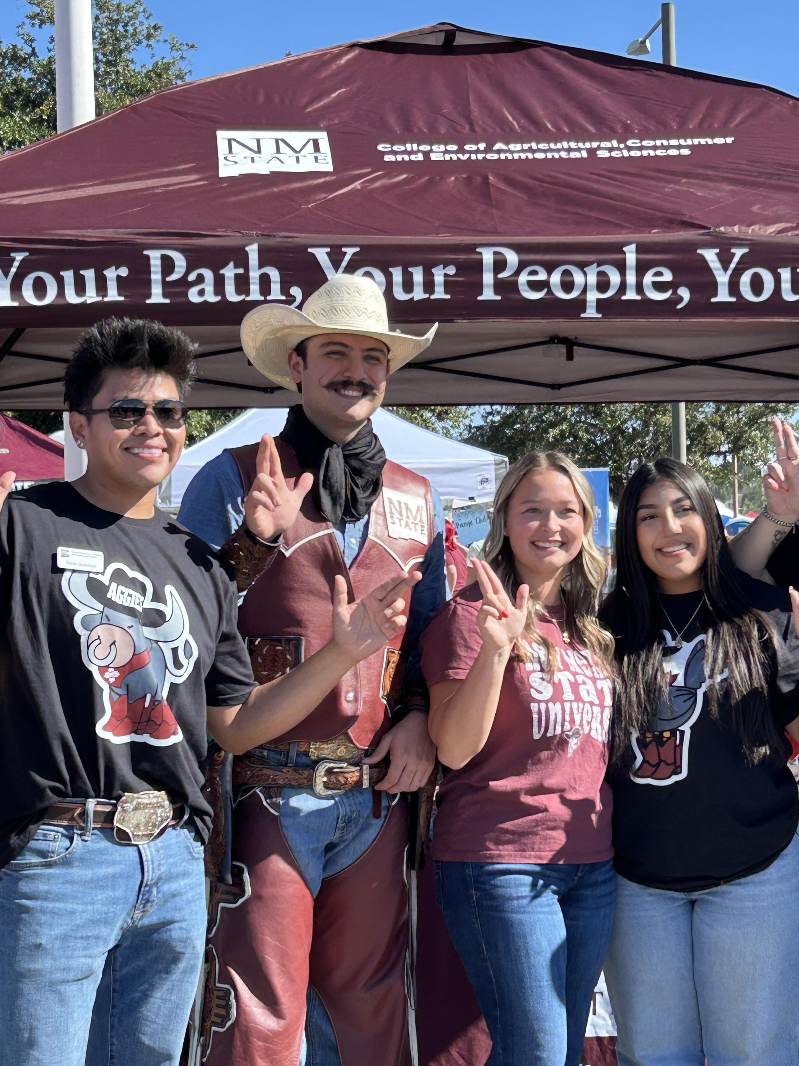 Three students pose with Pistol Pete at an NMSU College of Agricultural, Consumer and Environmental Sciences booth.