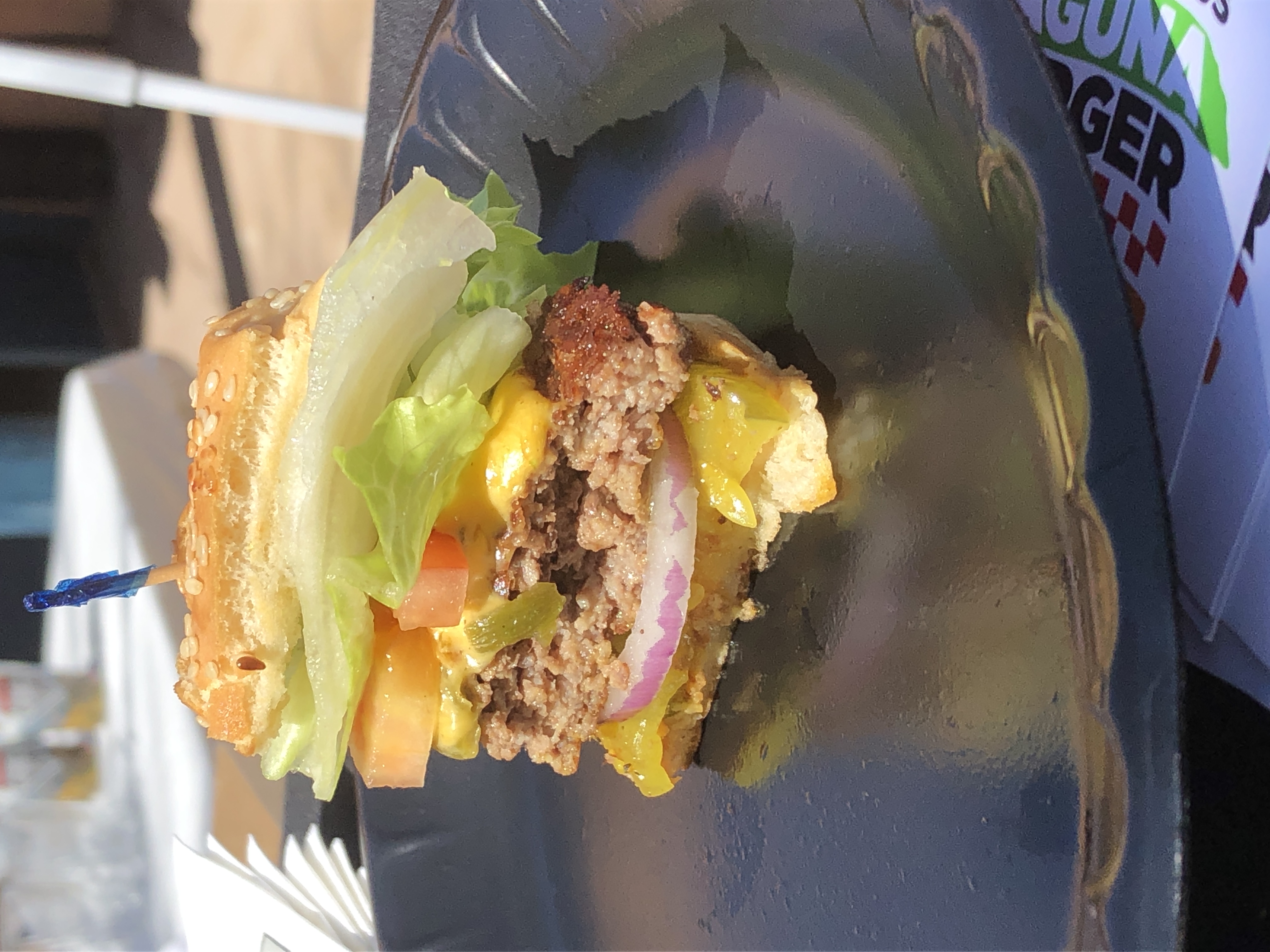 A sample slice of a green chile cheeseburger with pickles, onions, tomatoes and lettuce.