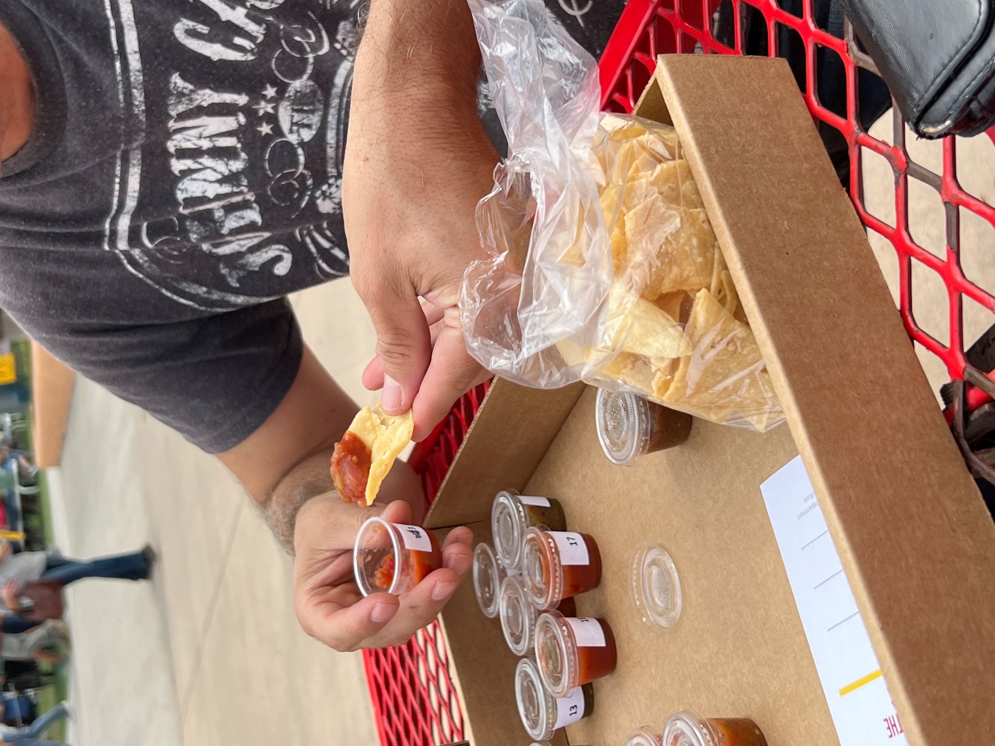 Someone sampling salsa from the Battle of the Salsas competition lineup.