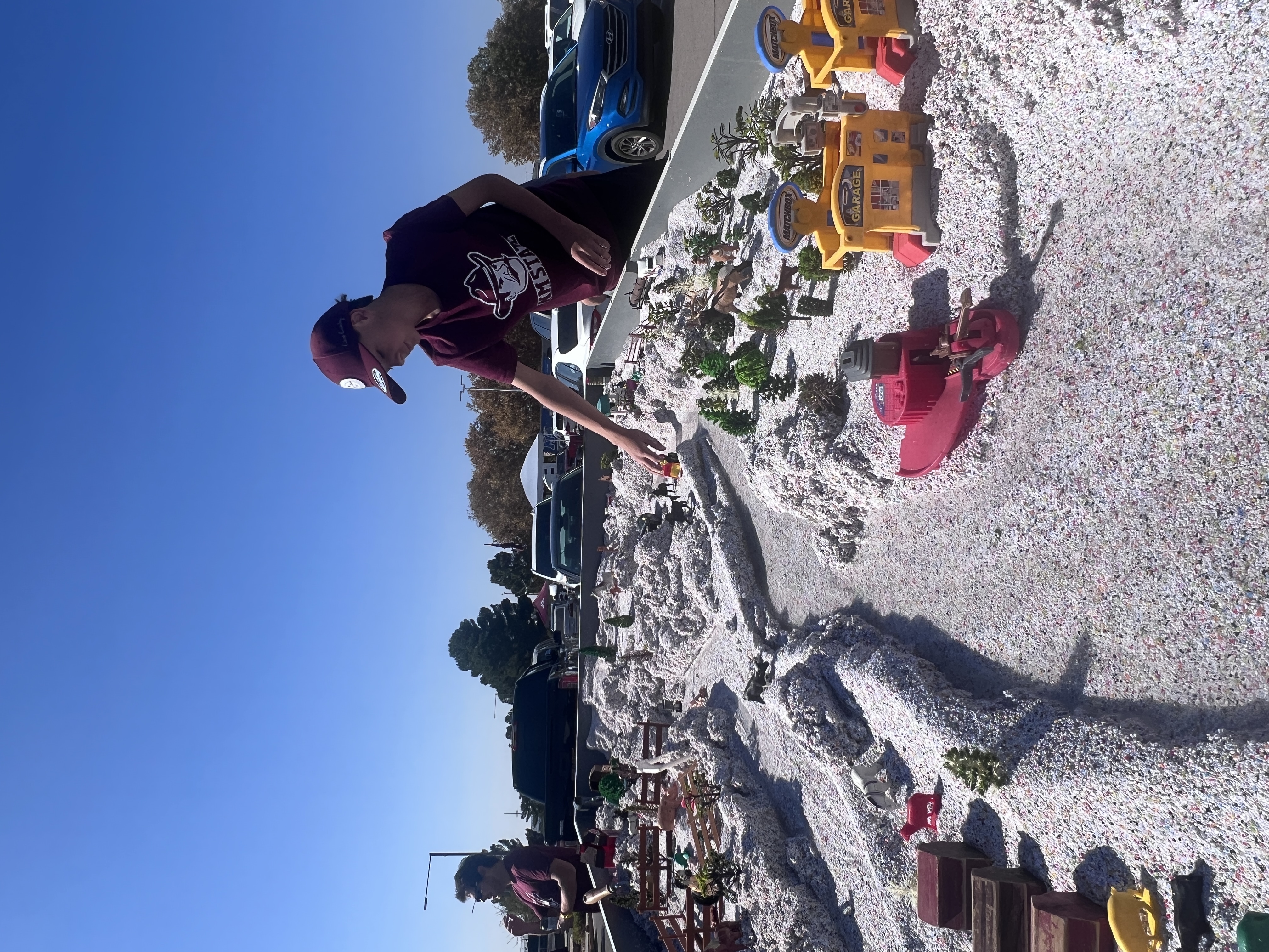 : Un niño con una camiseta carmesí de NMSU y una gorra de béisbol juega con una exhibición 3D interactiva de tierras agrícolas y sistemas de irrigación.