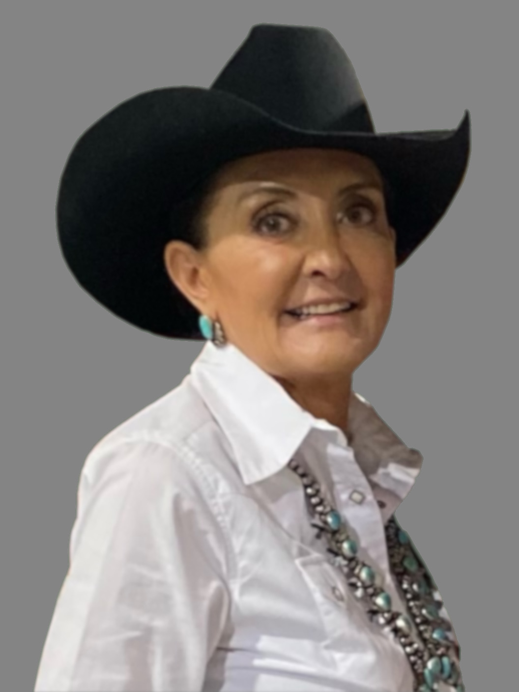 una mujer con un sombrero de vaquero negro y una camisa blanca con botones y joyas de color turquesa.