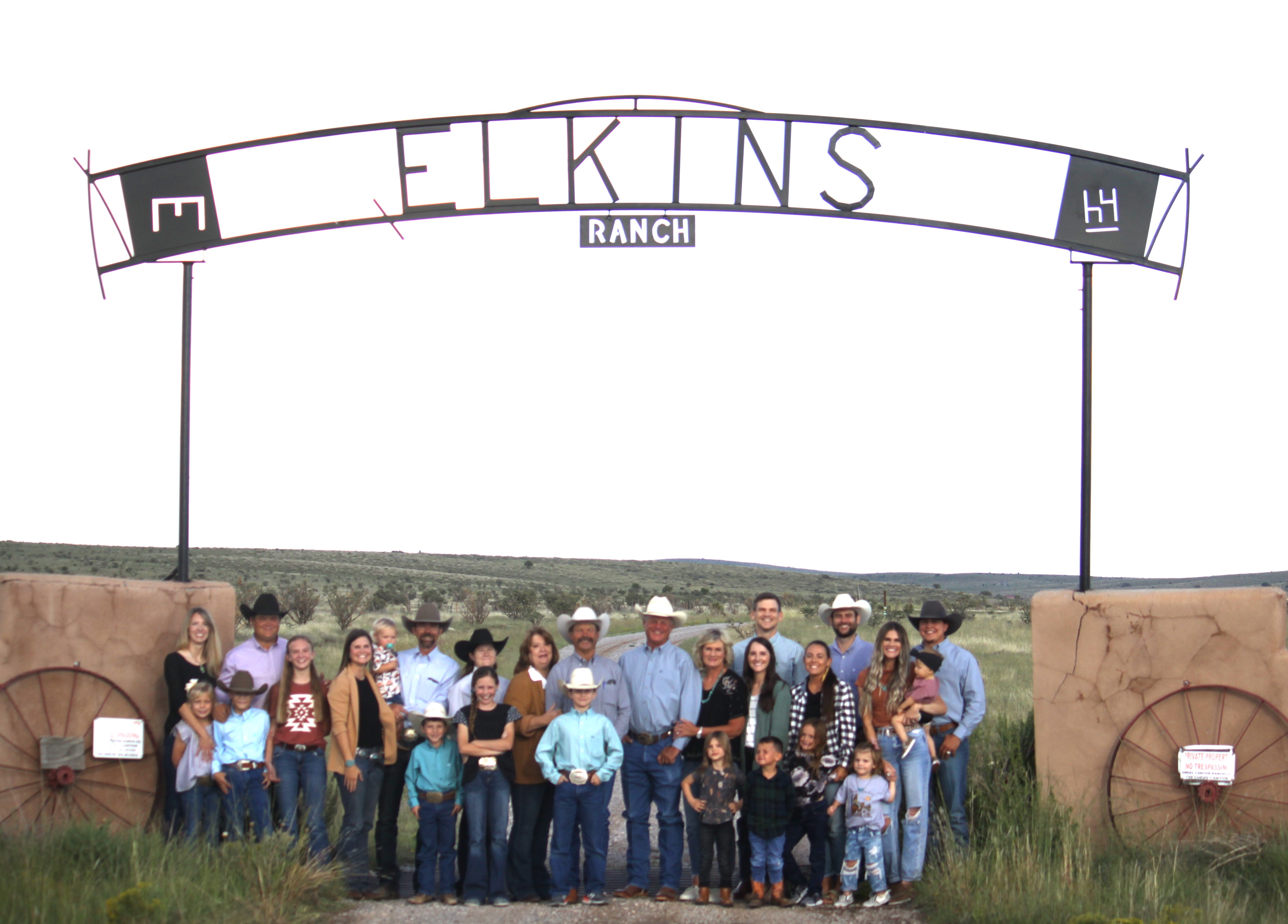Large family group posing under the Elkins Ranch sign at the ranch entrance.