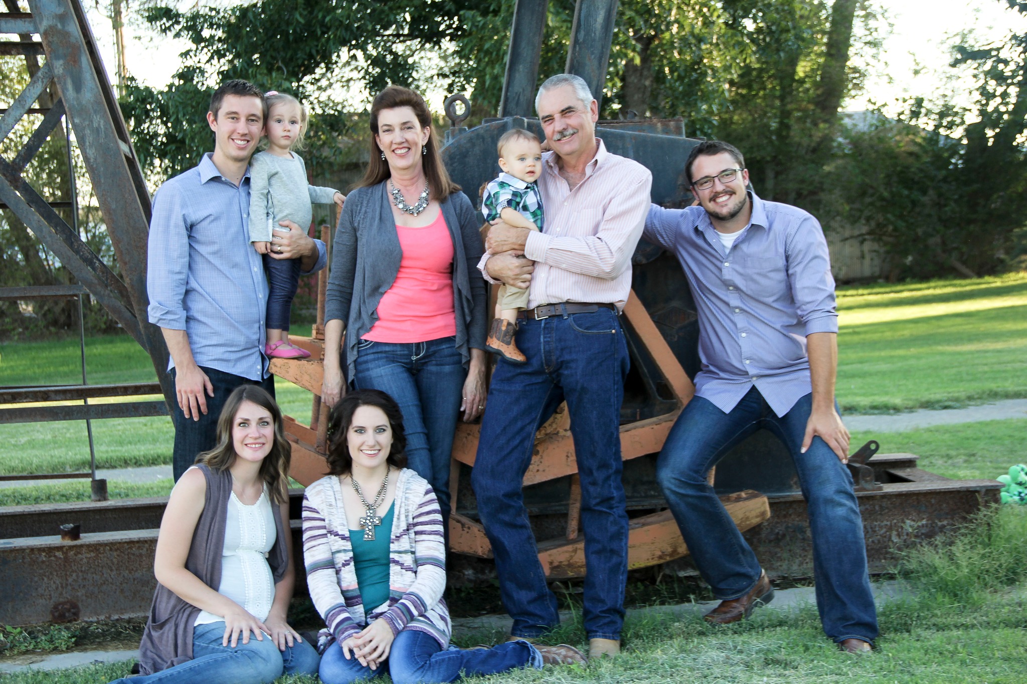 A family posing for a photo outside in front of farm equipment.