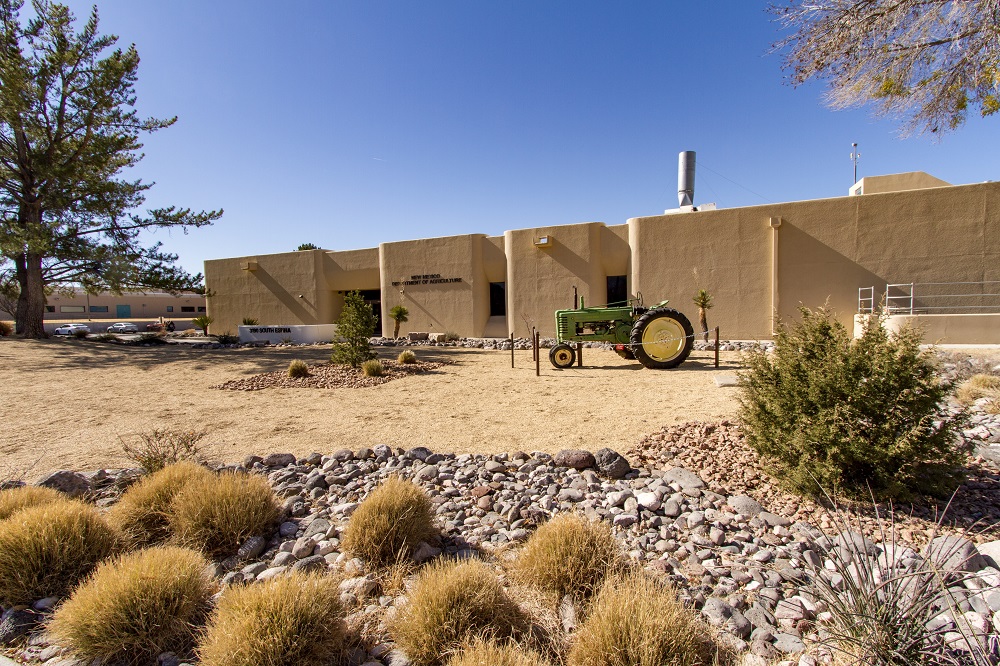 A tan building in the background, with a green tractor and rock landscaping in the foreground