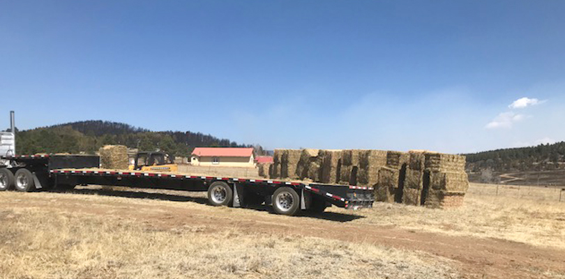 a truck bed with stacks of hay out in a valley.